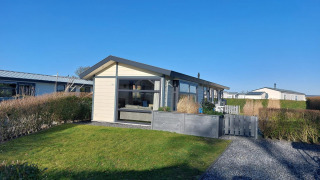 Chalet Velthorst au EuroParcs Parc du Soleil, Pays-Bas, pelouse verte, haies et ciel bleu ensoleillé.