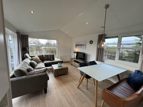 Gemütliches Wohnzimmer in der Velthorst-Hütte bei EuroParcs Parc du Soleil, Niederlande, mit Sofa und Tisch.