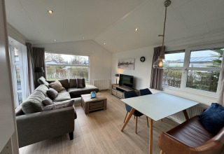 Gemütliches Wohnzimmer in der Velthorst-Hütte bei EuroParcs Parc du Soleil, Niederlande, mit Sofa und Tisch.