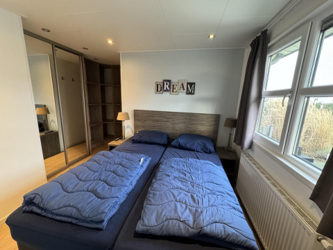 Dormitorio en la cabaña Velthorst en EuroParcs Parc du Soleil, Países Bajos, con ropa de cama azul.