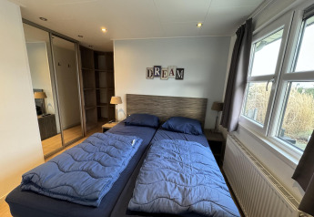 Camera da letto nella baita Velthorst di EuroParcs Parc du Soleil, Paesi Bassi, con biancheria blu.