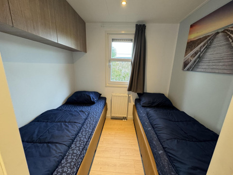 Dormitorio en la cabaña Velthorst de EuroParcs Parc du Soleil con dos camas individuales y decoración sencilla.