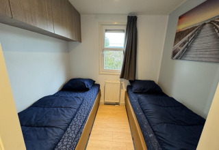 Dormitorio en la cabaña Velthorst de EuroParcs Parc du Soleil con dos camas individuales y decoración sencilla.