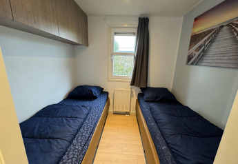 Chambre de la cabane Velthorst à EuroParcs Parc du Soleil avec deux lits simples et une déco moderne.