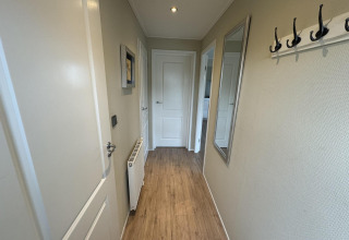 Hal van een chalet in Velthorst, EuroParcs Parc du Soleil Nederland, met houten vloer en kapstokken.