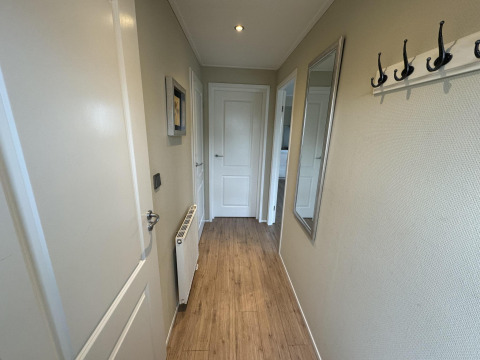 Pasillo de una cabaña en Velthorst, EuroParcs Parc du Soleil Países Bajos, con suelo de madera y espejo.