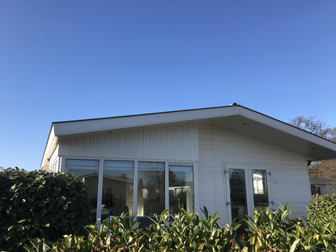 Weiße Velthorst-Hütte im EuroParcs Parc du Soleil Niederlande, große Fenster und klare Himmel.