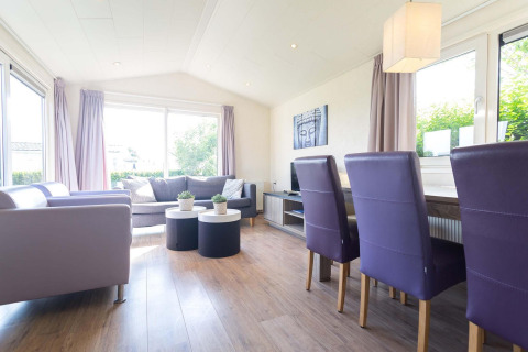 Salon moderne du chalet Berkel à EuroParcs Parc du Soleil, Pays-Bas, avec chaises violettes et lumière naturelle.