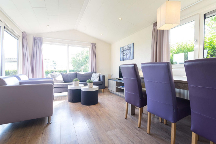 Sala moderna en la cabaña Berkel de EuroParcs Parc du Soleil, Países Bajos, con sillas moradas y luz natural.