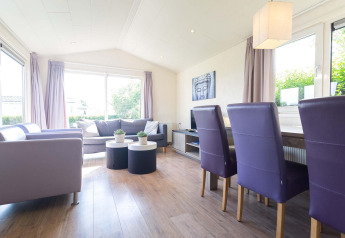 Salon moderne du chalet Berkel à EuroParcs Parc du Soleil, Pays-Bas, avec chaises violettes et lumière naturelle.