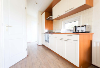 Cocina moderna en la cabaña Berkel de EuroParcs Parc du Soleil, Países Bajos, con gabinetes blancos.