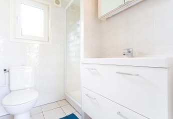 Baño luminoso con inodoro, ducha y mueble blanco en la cabaña Berkel de EuroParcs Parc du Soleil, Países Bajos.