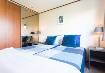 Dormitorio luminoso y moderno en una cabaña Berkel de EuroParcs Parc du Soleil en los Países Bajos, con detalles azules.