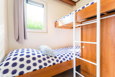 Chambre lumineuse avec lits superposés, meubles en bois et fenêtre dans la cabane Berkel à EuroParcs Parc du Soleil, Pays-Bas.