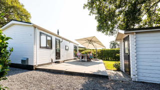 Terrasse extérieure du chalet Berkel à EuroParcs Parc du Soleil, Pays-Bas, avec des personnes sous un parasol.