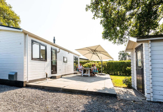 Terrasse extérieure du chalet Berkel à EuroParcs Parc du Soleil, Pays-Bas, avec des personnes sous un parasol.