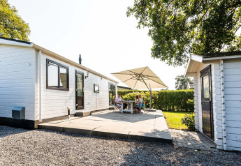 Außenterrasse der Berkel-Hütte im EuroParcs Parc du Soleil, Niederlande, mit Menschen unter einem Sonnenschirm.