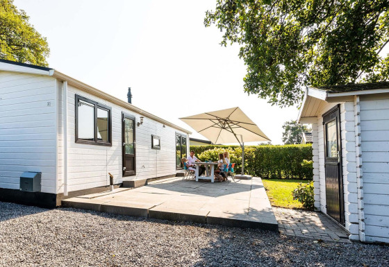 Terrasse extérieure du chalet Berkel à EuroParcs Parc du Soleil, Pays-Bas, avec des personnes sous un parasol.