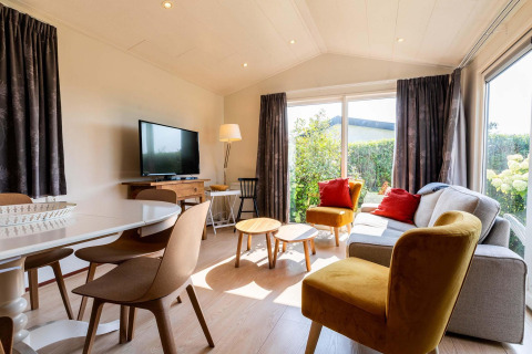 Bright and cozy living room in a Berkel cabin at EuroParcs Parc du Soleil, featuring large windows and modern decor.