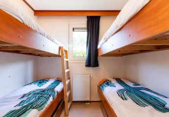 Lichte kamer met houten stapelbedden en cactusbedlinnen in de Berkel-cabine bij EuroParcs Parc du Soleil.
