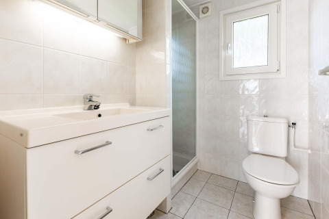 Salle de bain lumineuse avec lavabo, toilettes et douche dans le chalet Berkel à EuroParcs Parc du Soleil.