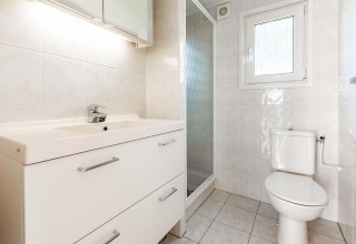 Salle de bain lumineuse avec lavabo, toilettes et douche dans le chalet Berkel à EuroParcs Parc du Soleil.