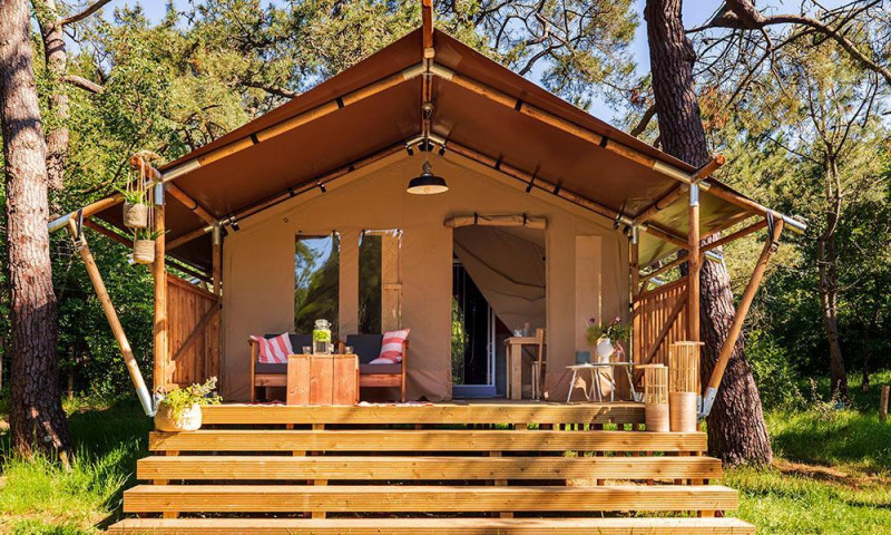 Comet 27 Lodges safaritent bij Petite Suisse in België met houten veranda en bosrijke omgeving.