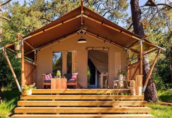 Tienda safari Comet 27 Lodges en Petite Suisse, Bélgica, con terraza acogedora y rodeada de árboles.