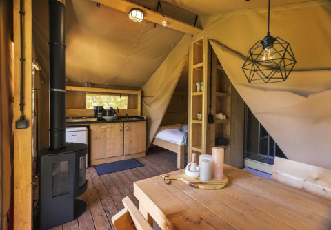 Interior de la tienda safari Comet 27 Lodges en Petite Suisse, Bélgica, con decoración de madera y cocina.