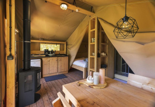 Interior de la tienda safari Comet 27 Lodges en Petite Suisse, Bélgica, con decoración de madera y cocina.