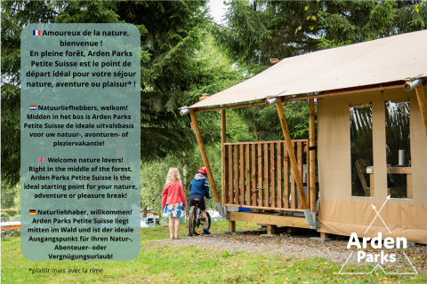 Dos niños y un adulto junto a una tienda glamping en el bosque, en Arden Parks Petite Suisse, Bélgica.