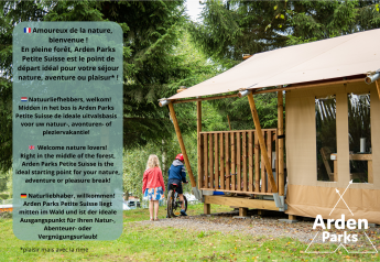 To børn og en voksen ved et luksustelt i skoven. Tekst promoverer Arden Parks Petite Suisse glamping.