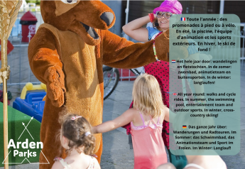 Børn leger med en maskot og en voksen ved et glampingområde, reklameskilt for Arden Parks ses.
