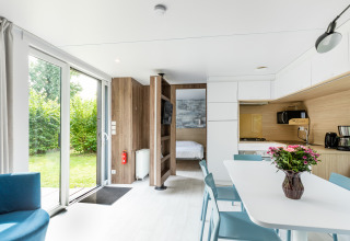 Interior luminoso del Taos XL Delux mobile home en Baalse Hei, Bélgica, con cocina, comedor y vista al jardín.
