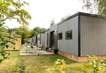 Buitenaanzicht van Taos XL Delux Mobile home lodge op Baalse Hei in België, met omringend groen.