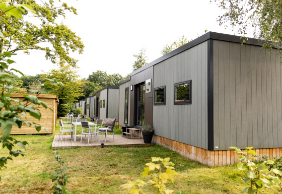 Buitenaanzicht van Taos XL Delux Mobile home lodge op Baalse Hei in België, met omringend groen.