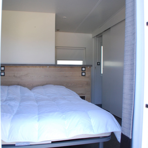 Slaapkamer van Taos XL Delux Mobile home lodge op Baalse Hei, België, met helder interieur en dubbel bed.