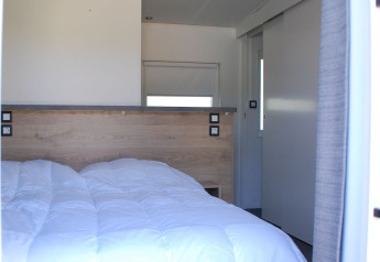 Slaapkamer van Taos XL Delux Mobile home lodge op Baalse Hei, België, met helder interieur en dubbel bed.
