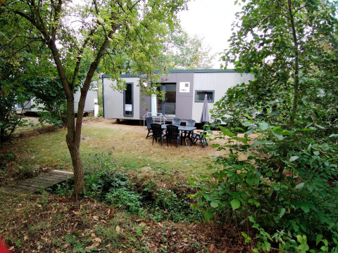 Buitenaanzicht van de Taos XL Delux Mobile home lodge bij Baalse Hei, België, omringd door bomen.