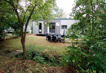 Buitenaanzicht van de Taos XL Delux Mobile home lodge op Baalse Hei, België, omgeven door bomen.