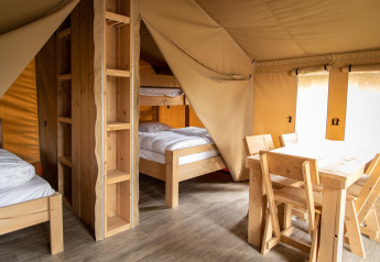 Vista interna di una tenda safari al Baalse Hei in Belgio, con arredi in legno e letti a castello.