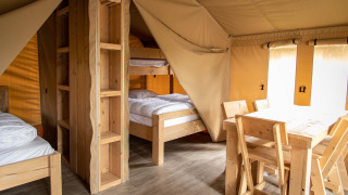 Innenaufnahme eines Safarizeltes auf dem Baalse Hei in Belgien mit Holzmöbeln und Etagenbetten.