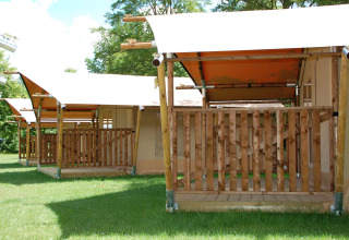 Safari tents at Baalse Hei in Belgium, featuring wooden decks and green grass under a sunny sky.