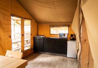 Interieur van een safaritentkeuken bij Baalse Hei in België met fornuis, magnetron en tafel.