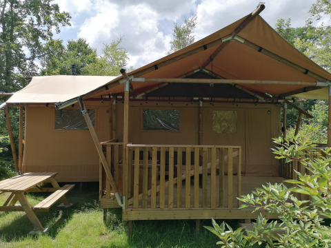 Safari tent Dreamer at Baalse Hei, Belgium, featuring a wooden terrace and bench in green nature.
