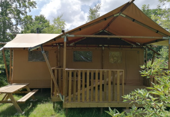 Safari telt Dreamer på Baalse Hei i Belgien, med træterrasse og bænk i frodige, grønne omgivelser.