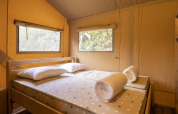 Soveområde i Safari tent Dreamer, Baalse Hei, Belgien, med enkeltsenge, puder og vinduer med udsigt.
