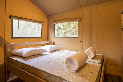 Zona notte nella tenda Safari Dreamer a Baalse Hei, Belgio, con letto matrimoniale, cuscini e finestre.