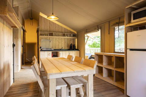 Safari-tent Dreamer op Baalse Hei in België met eettafel, houten meubels en ingerichte keuken.