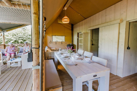 Binnen- en buitenaanzicht van een Ranger Lodge safaritent op Baalse Hei, België, met eet- en zithoek.